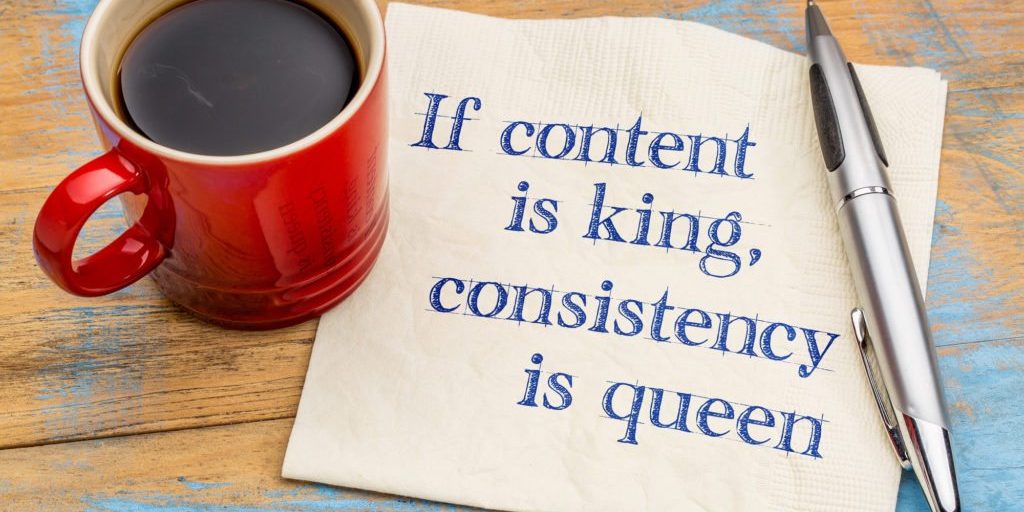 If content is king, consistency is queen - blogging and social media tip - handwriting on a napkin with a cup of coffee